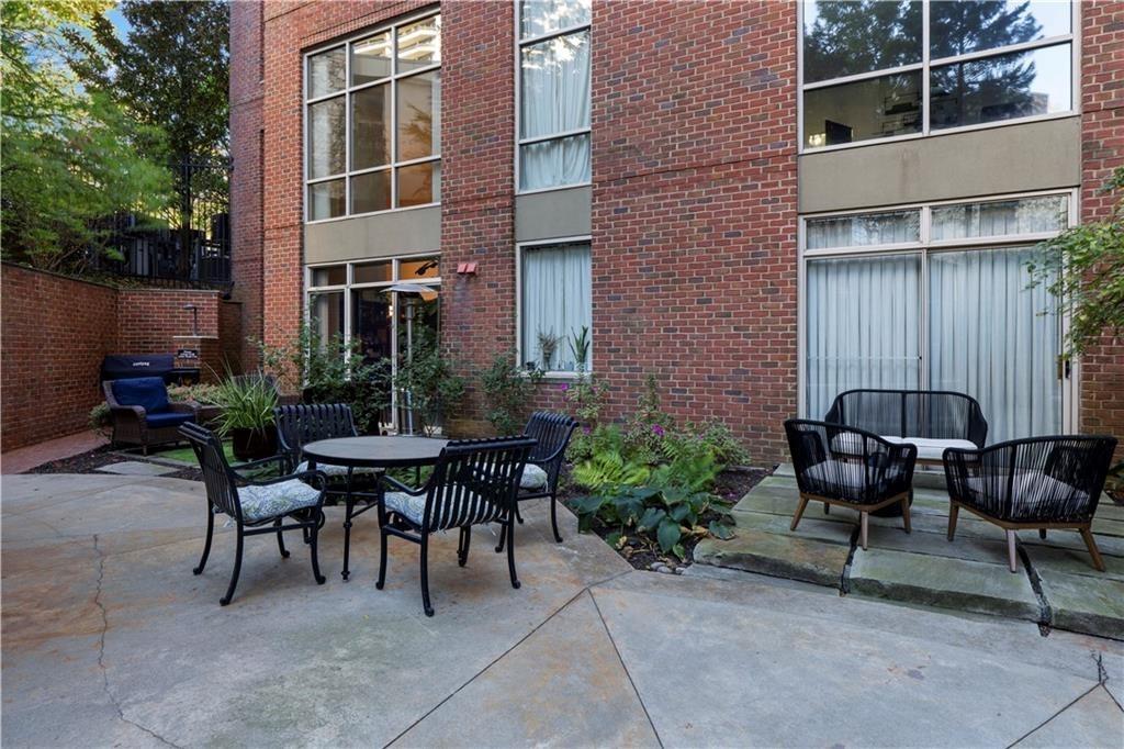 2626 Peachtree Road Northwest, Unit 704 Atlanta, GA 30305 - Photo 20 of 23 a backyard of a house with dining table and chairs with plants and trees