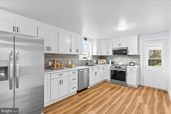 a kitchen with stainless steel appliances granite countertop a refrigerator a stove top oven a sink and dishwasher with wooden floor