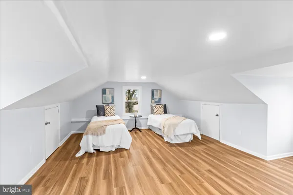 a spacious bedroom with two beds lamp and a potted plant
