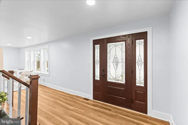 a view of a hallway to a livingroom with wooden floor and windows