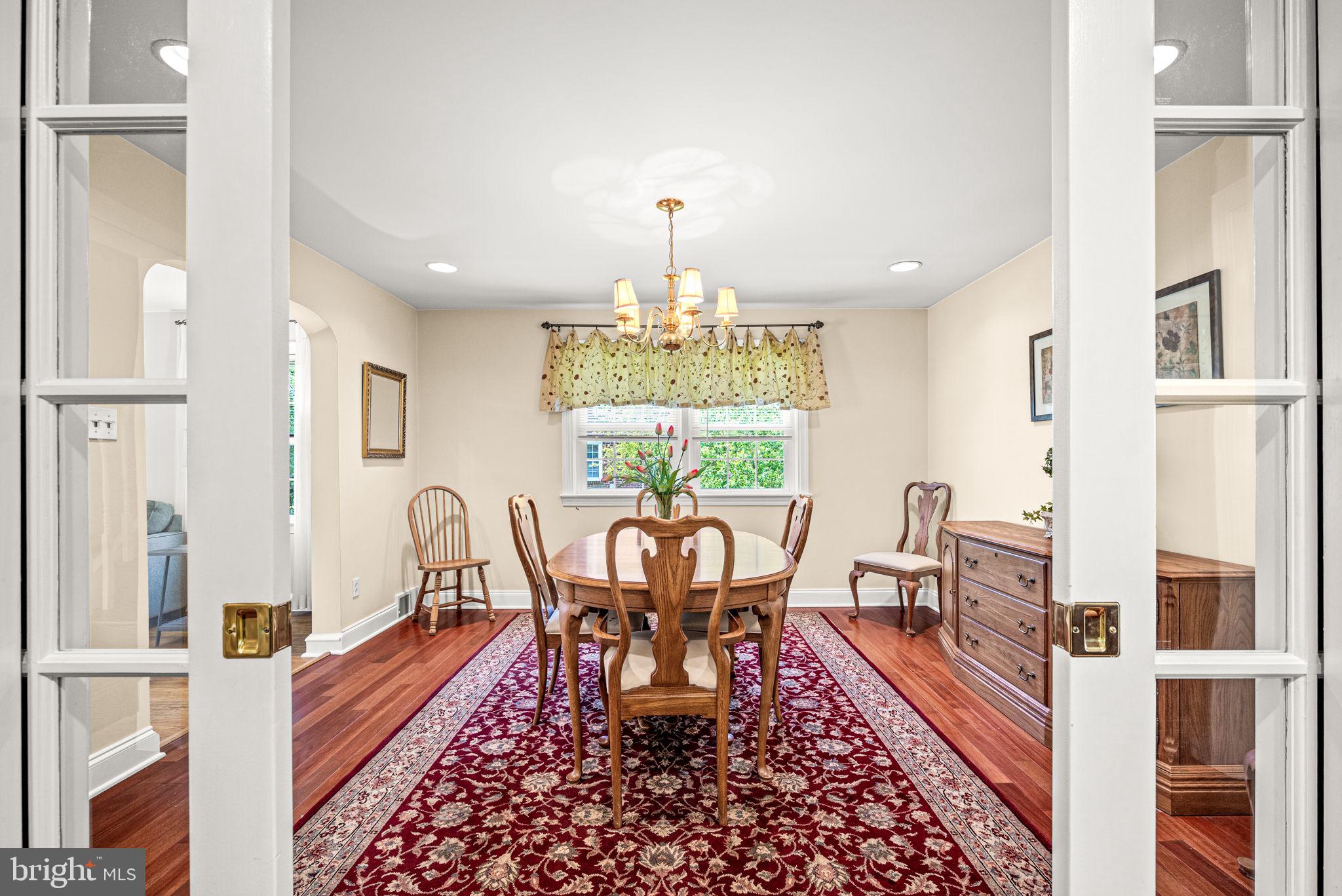 107 Lombardy Drive Wallingford, PA 19086 - Photo 8 of 36 a dining room with wooden floor a chandelier a wooden table and chairs