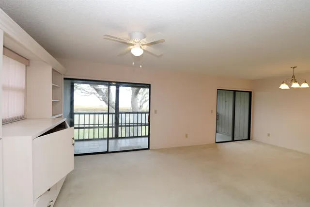 a view of a livingroom with a chandelier fan and windows