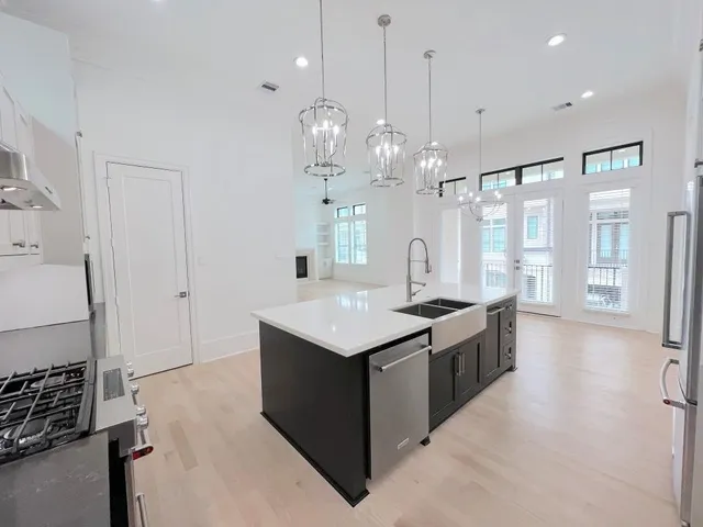 a large kitchen with kitchen island a stove a sink dishwasher and a dining table with wooden floor