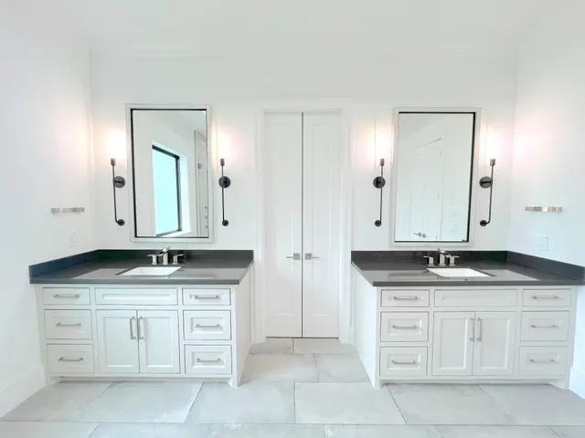 a bathroom with granite countertop white cabinets and a sink
