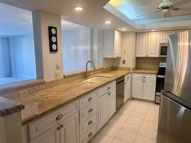 a kitchen with granite countertop a sink stainless steel appliances and cabinets