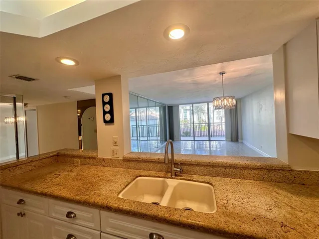 a view of a kitchen with granite countertop sink and natural light