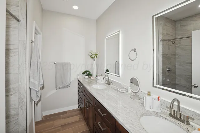 a bathroom with a granite countertop double vanity sink mirror and shower