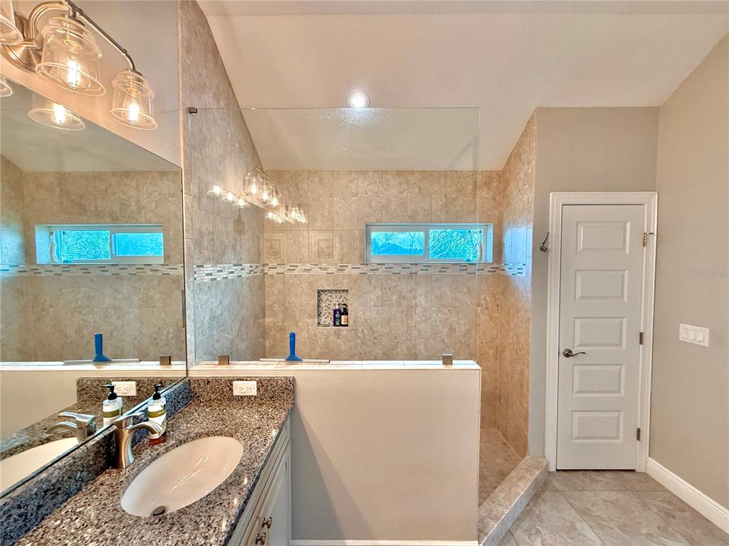 2569 Palm Avenue Flagler Beach, FL 32136 - Photo 34 of 69 a bathroom with a granite countertop sink a mirror and a bathtub