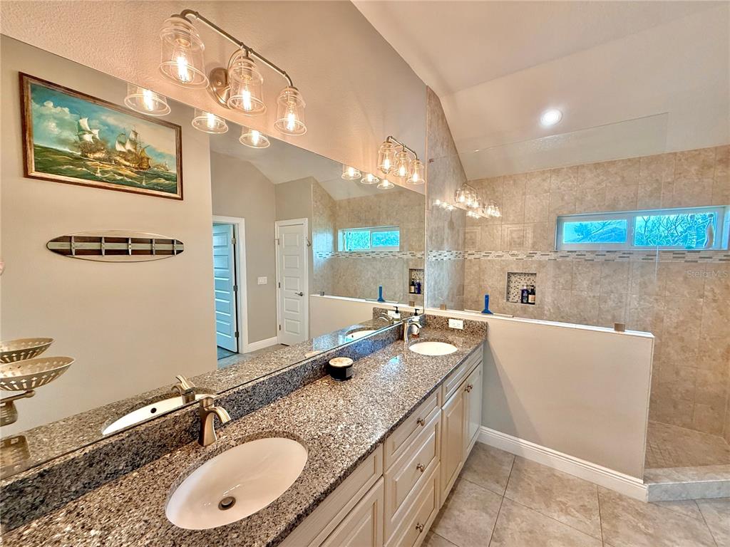 2569 Palm Avenue Flagler Beach, FL 32136 - Photo 35 of 69 a bathroom with a granite countertop sink a mirror and a bathtub