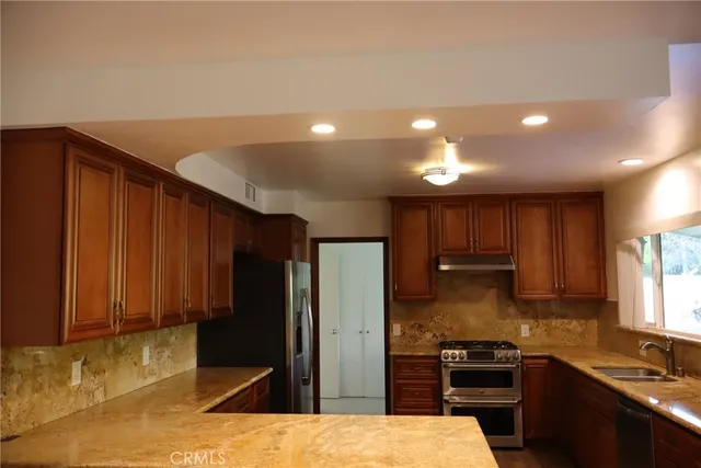 a kitchen with stainless steel appliances kitchen island granite countertop a refrigerator stove and sink