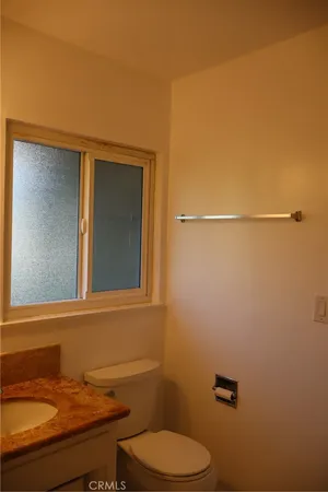 a bathroom with a granite countertop toilet and a sink