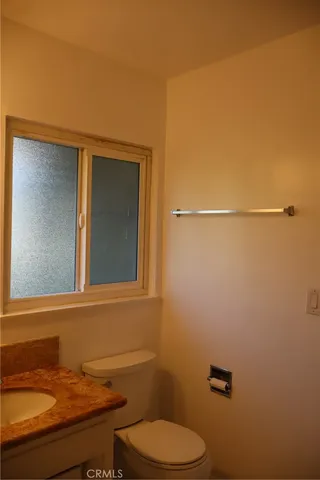 a bathroom with a granite countertop toilet and a sink