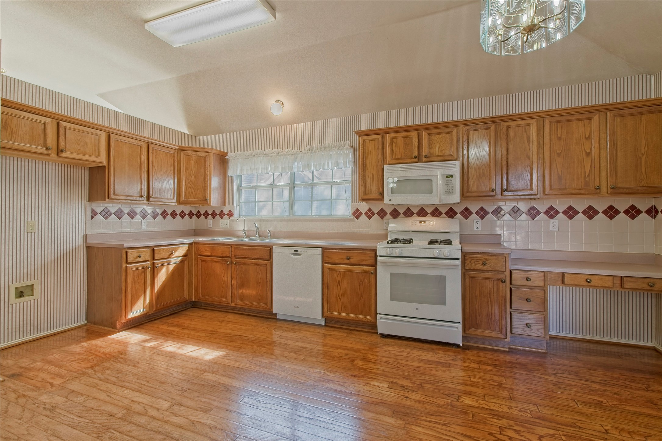 108 Rio Vista Drive Georgetown, TX 78626 - Photo 10 of 36 Kitchen with white appliances, light countertops, light wood-style floors, radiator, and wallpapered walls