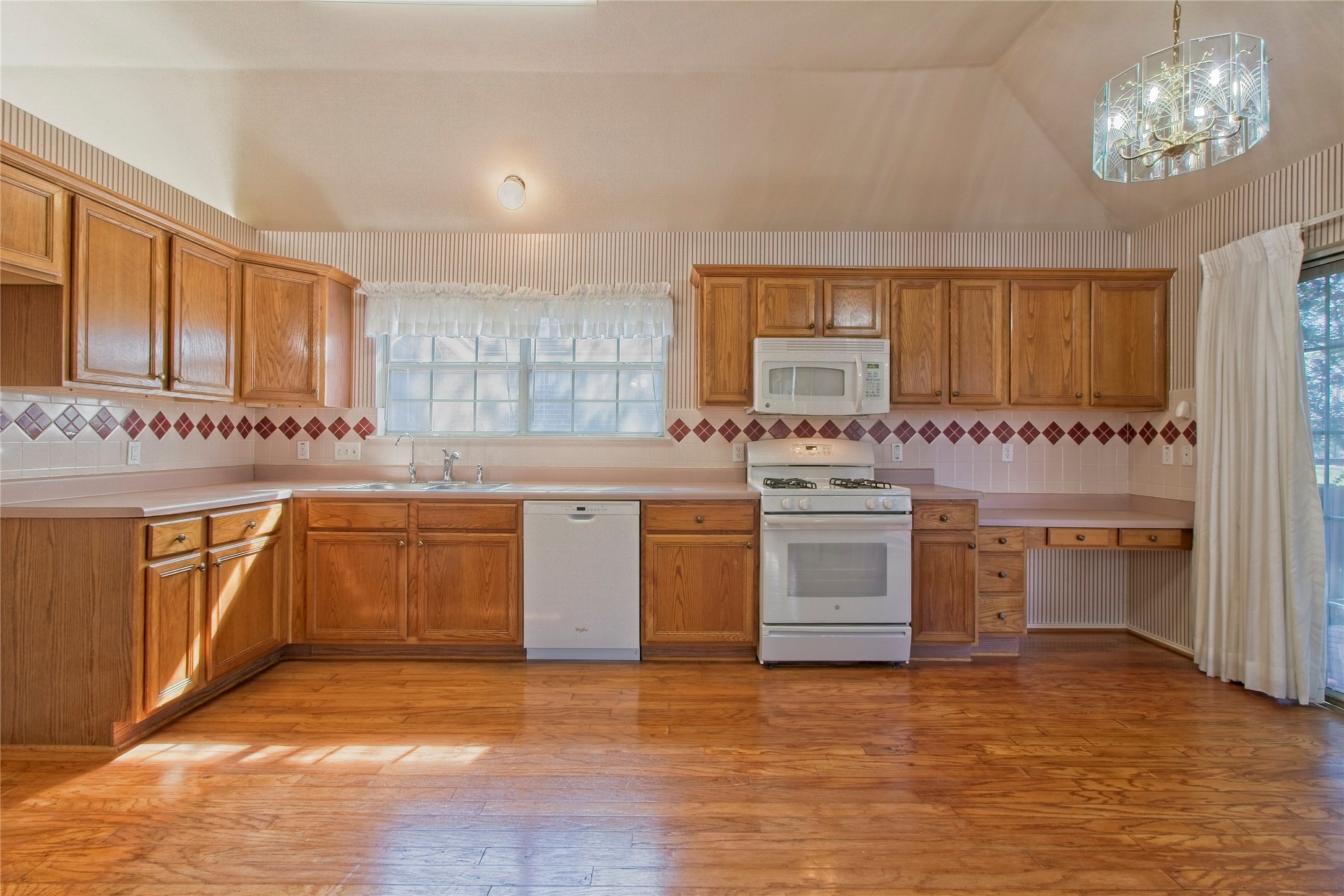 108 Rio Vista Drive Georgetown, TX 78626 - Photo 15 of 36 Kitchen with white appliances, light countertops, light wood-style flooring, vaulted ceiling, and backsplash