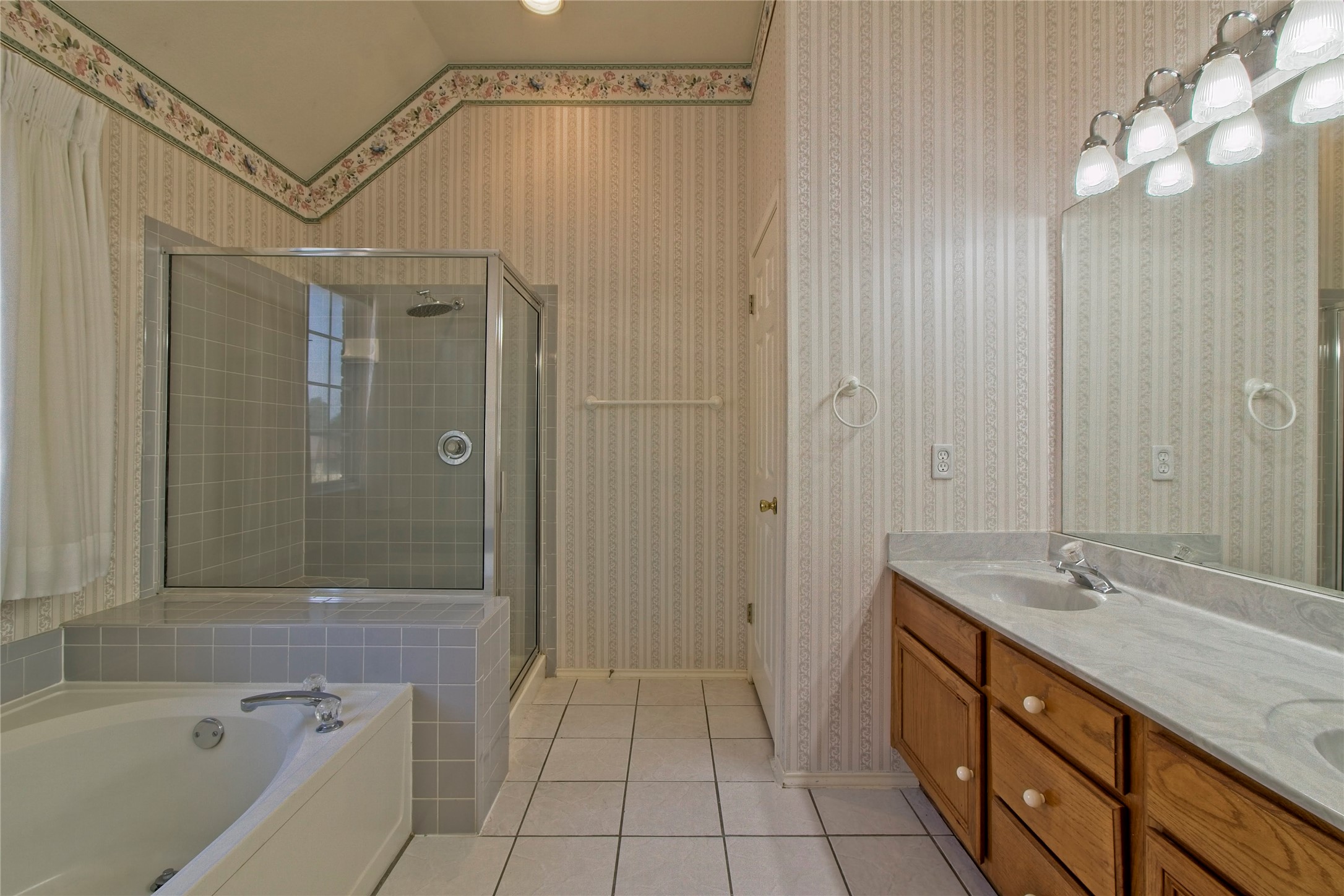 108 Rio Vista Drive Georgetown, TX 78626 - Photo 18 of 36 Bathroom featuring double vanity, light tile patterned floors, a shower stall, and a garden tub