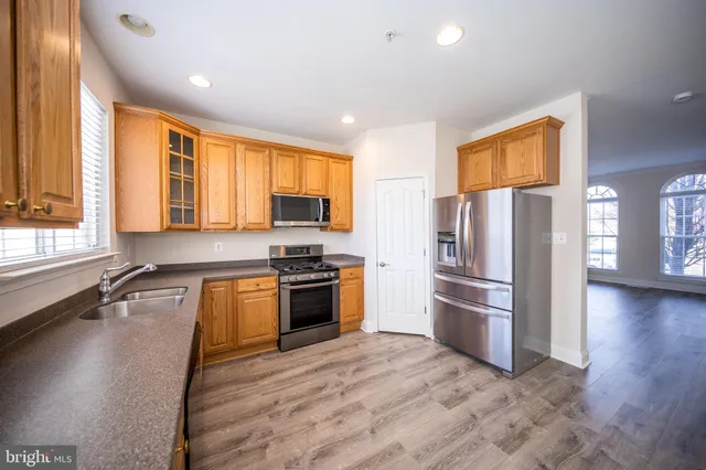 a kitchen with granite countertop a refrigerator stove top oven and sink