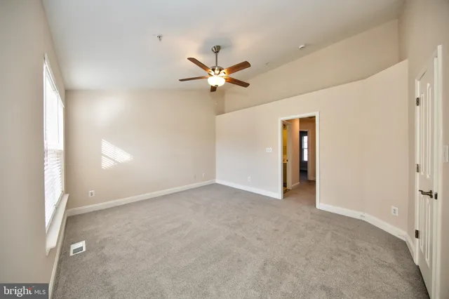 an empty room with closet and a ceiling fan