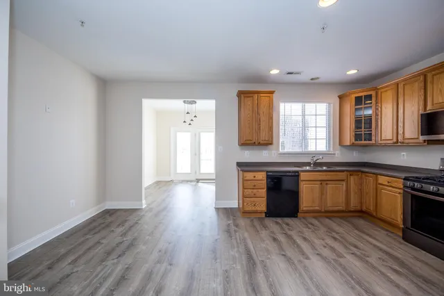 a kitchen with granite countertop a stove top oven a sink dishwasher and a refrigerator with wooden floor