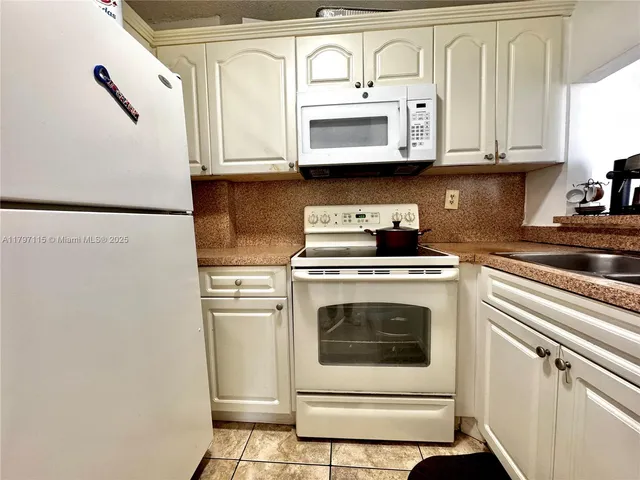 a kitchen with stainless steel appliances granite countertop white cabinets sink and a granite counter top