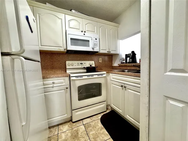 a kitchen with white cabinets and white appliances
