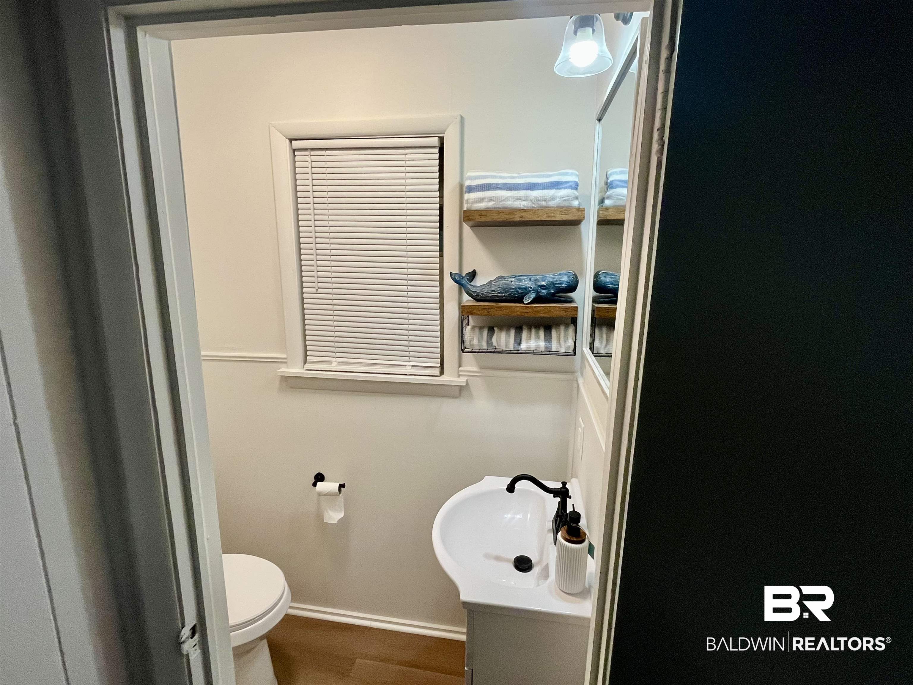 3105 Bryant Road Mobile, AL 36605 - Photo 29 of 39 Compact powder room featuring a pedestal sink with matte black faucet, wall-mounted mirror, and wood-finish flooring