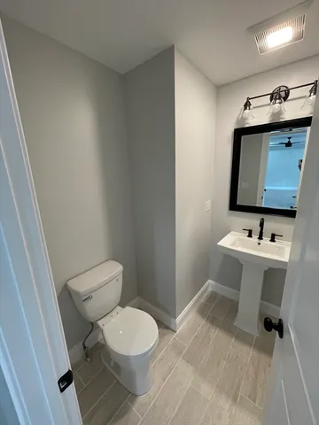 a view of bathroom with toilet window and hardwood floor