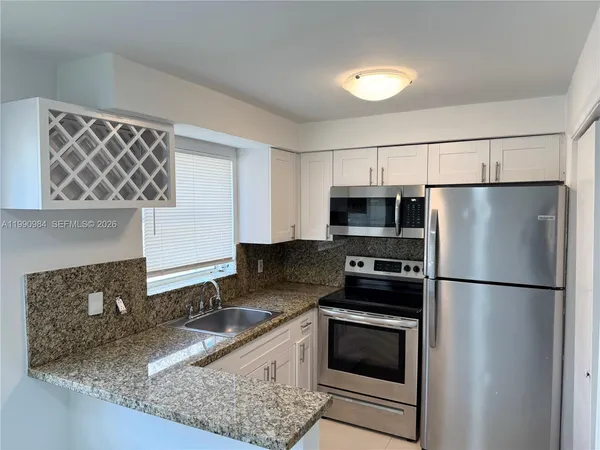a kitchen with granite countertop a refrigerator stove and microwave