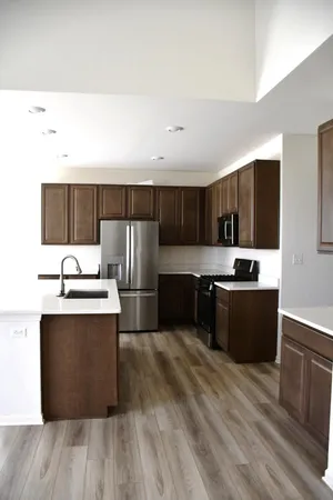 a large kitchen with stainless steel appliances wooden cabinets and a wooden floor