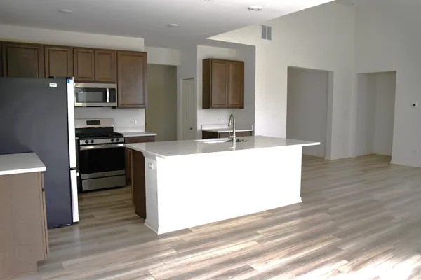 a kitchen with stainless steel appliances a sink and wooden floor