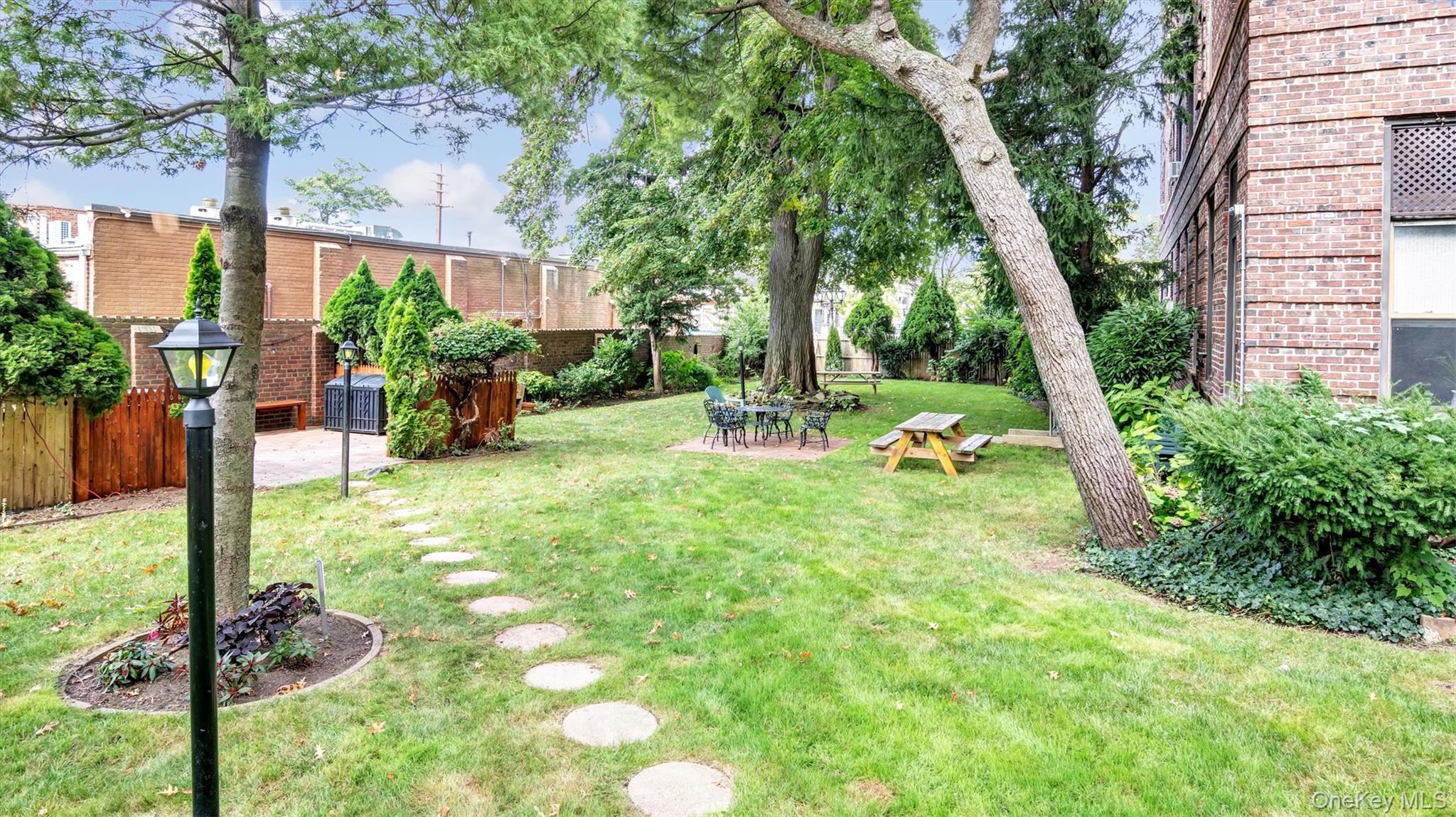 8 Barstow Road, Unit 7H Great Neck, NY 11021 - Photo 16 of 27 a view of a backyard with couches plants and large trees