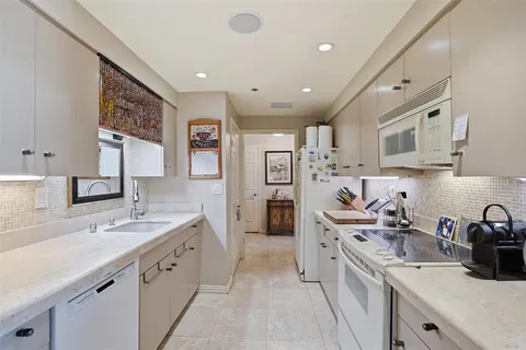 a large white kitchen with stainless steel appliances granite countertop a sink and cabinets