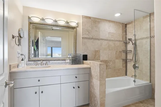 a bathroom with a bathtub shower sink vanity and mirror