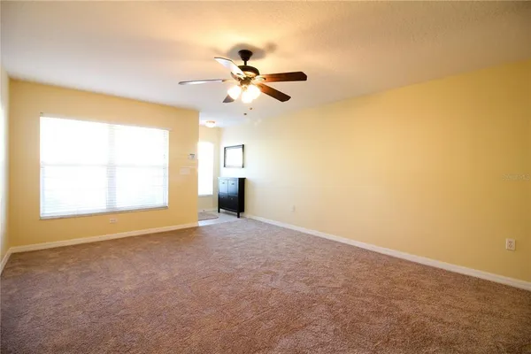 a view of an empty room with chandelier fan and a window