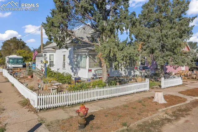 a view of a house with a small yard and wooden fence