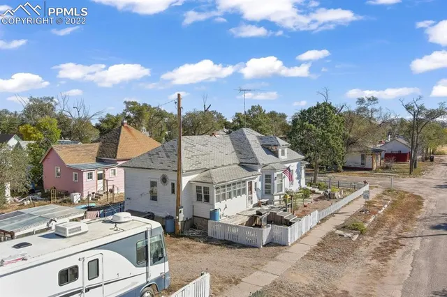 a view of a white house with a big yard and potted plants