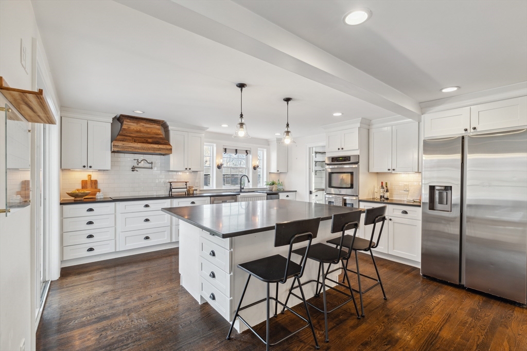 83 County Road Reading, MA 01867 - Photo 17 of 42 a kitchen with stainless steel appliances kitchen island granite countertop a table chairs cabinets and wooden floor
