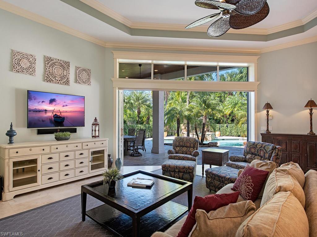7347 Stonegate Drive Naples, FL 34109 - Photo 7 of 20 a living room with furniture a flat screen tv and a floor to ceiling window