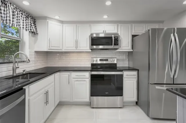 a kitchen with white cabinets and stainless steel appliances