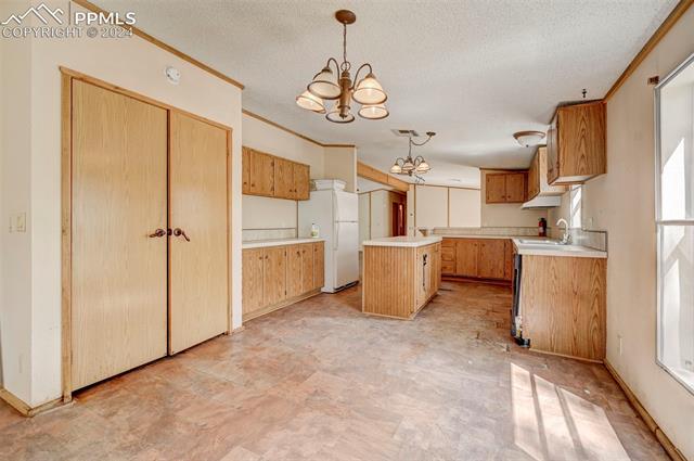 2259 Pathfinder Road Florissant, CO 80816 - Photo 19 of 33 Kitchen with a chandelier, white refrigerator, decorative light fixtures, a center island, and light tile patterned flooring