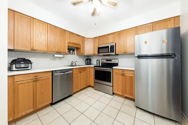 a kitchen with granite countertop a refrigerator a sink a stove top oven and cabinets