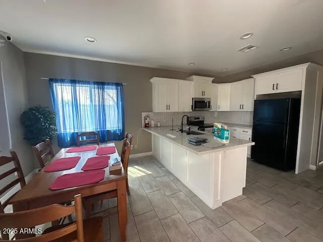 a kitchen with stainless steel appliances kitchen island granite countertop a refrigerator a stove top oven a sink dishwasher and white cabinets