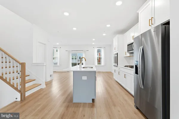 a large kitchen with a center island wooden floor stainless steel appliances and cabinets