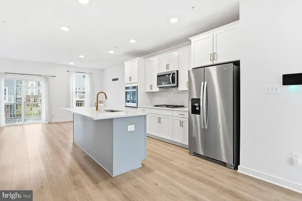 a kitchen with stainless steel appliances a refrigerator and wooden floor