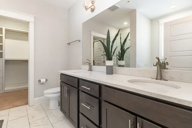 a bathroom with a double vanity sink toilet and a mirror