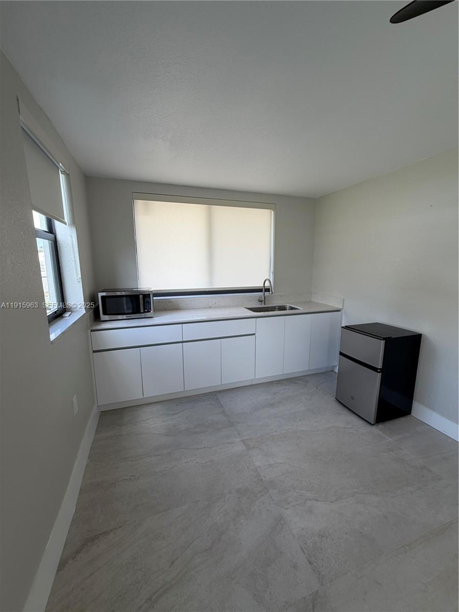7330 Southwest 11th Street, Unit EFFICIENCY Miami, FL 33144 - Photo 5 of 11 a kitchen with granite countertop a sink and a stove top oven
