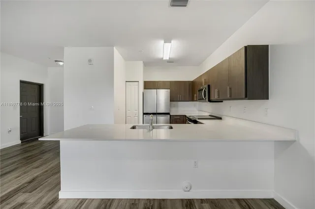 a large white kitchen with kitchen island granite countertop wooden cabinets and a sink