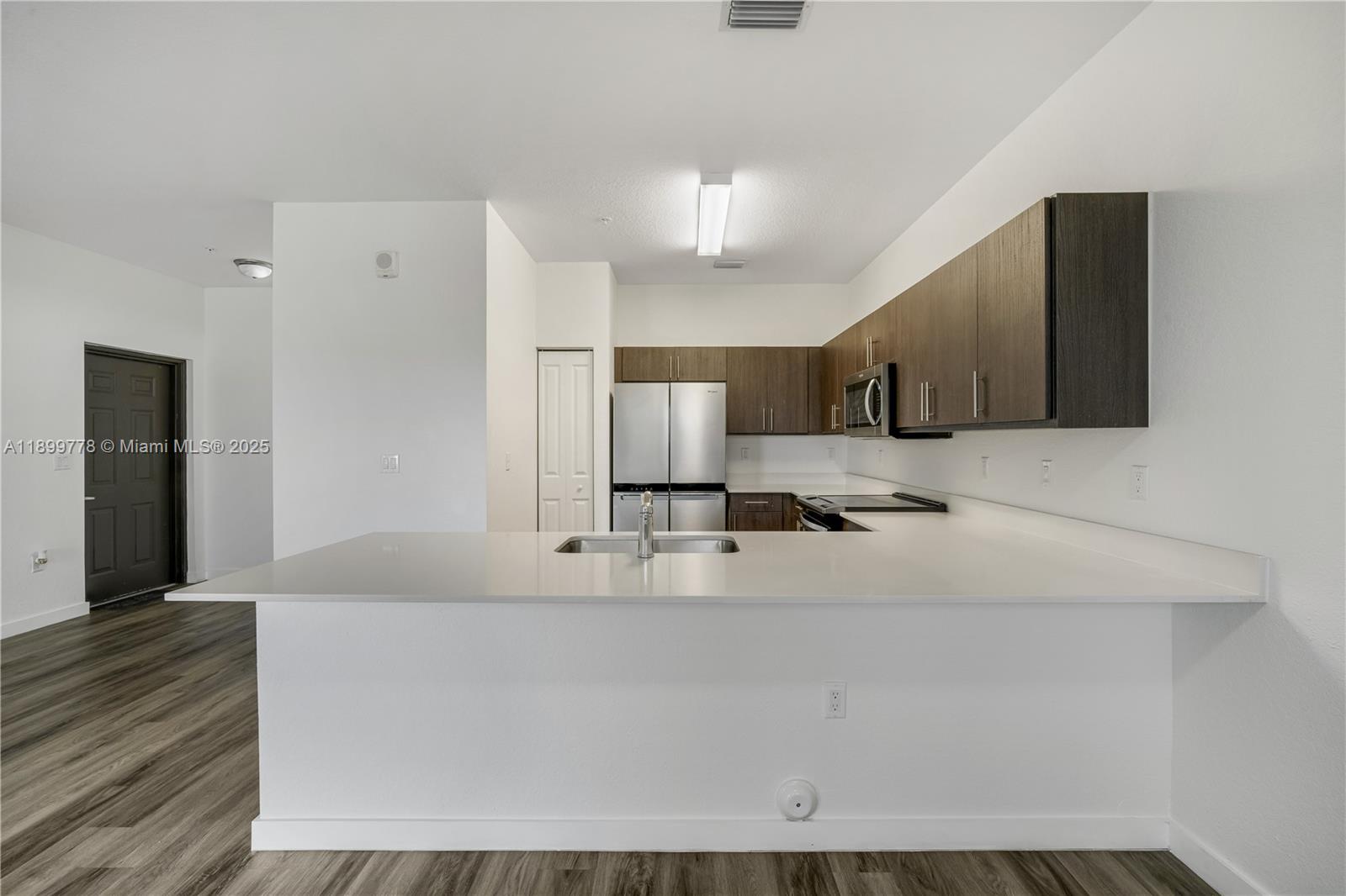 a large white kitchen with kitchen island granite countertop wooden cabinets and a sink