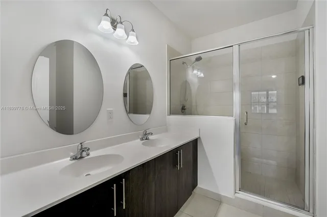 a bathroom with a double vanity sink mirror and shower