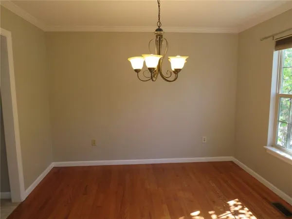 a view of a room with wooden floor chandelier and window