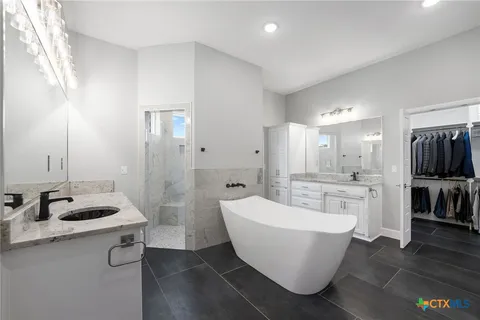 a bathroom with a white tub sink shower and mirror